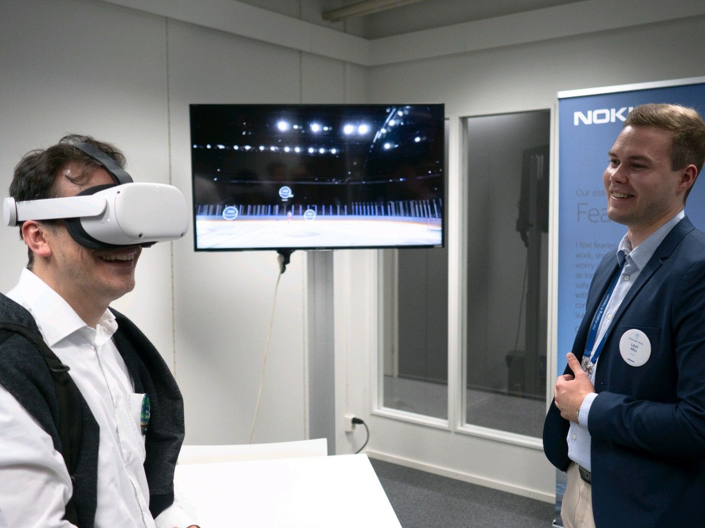 Lauri Alho observing a Nokia customer engaging with the Nokia Arena VR demo at the Nokia Radio World event, highlighting the practical application of metaverse technologies.