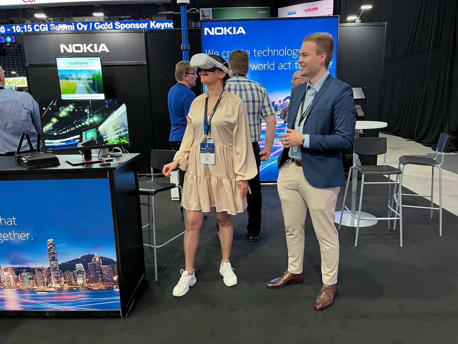Lauri Alho demonstrating to a participant the Nokia 5G mmWave multimedia use cases via a VR headset at Tampere Smart City Week 2022.