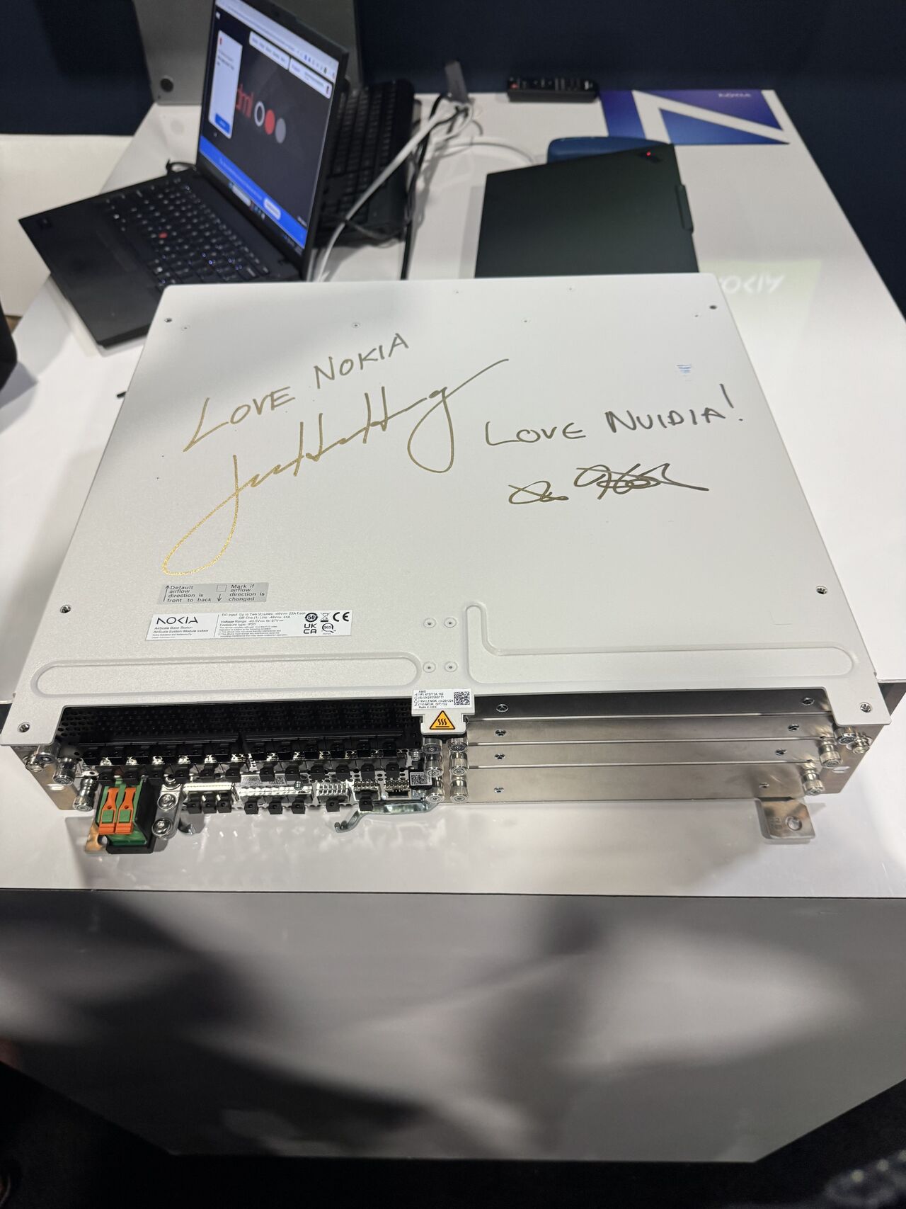Nokia 5G radio unit, signed by Nokia CEO Justin Hotard and NVIDIA CEO Jensen Huang, symbolizing their strategic partnership to integrate NVIDIA GPUs for AI-RAN at the edge.